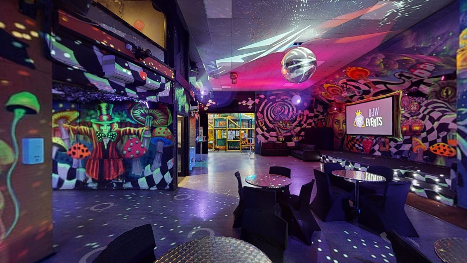The main hall at night: tables, the screen and the soft play under the disco lights