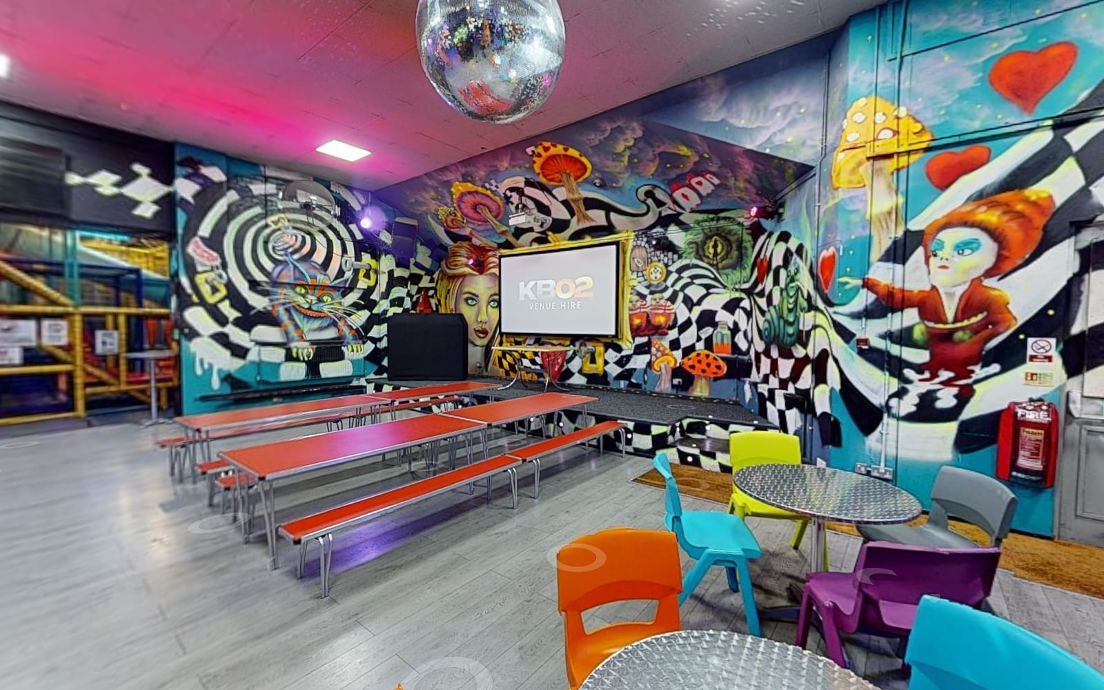 The main hall: the screen, long tables, the Wonderland murals and the soft play behind